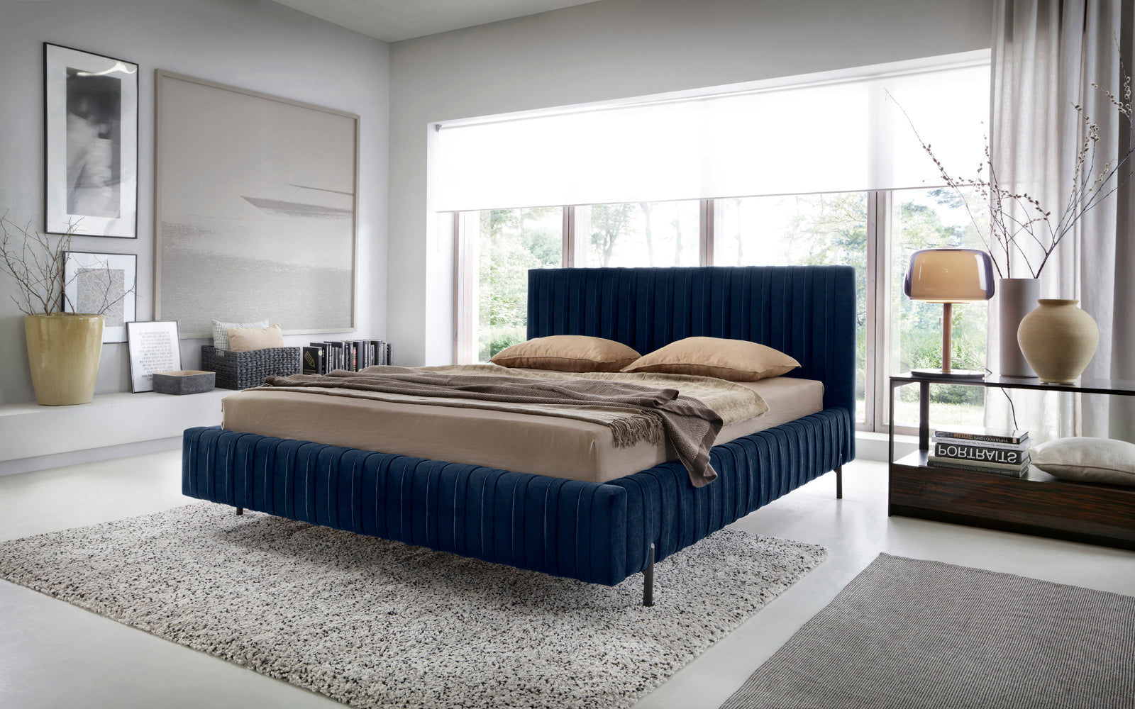 Łóżko Plissa 140×200 Velvetmat 40 granatowe w stylowej sypialni z dużym oknem, udekorowane beżową pościelą, narzutą i designerską lampką na szklanym stoliku.