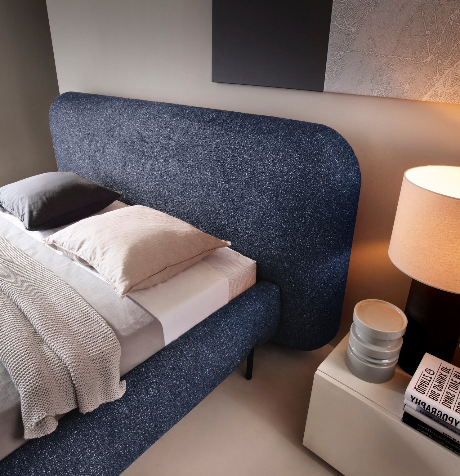 Zbliżenie na zagłówek łóżka Pointt w tkaninie Breona 40 niebieskiej, widok z boku, pościelone łóżko z poduszkami i kocem.