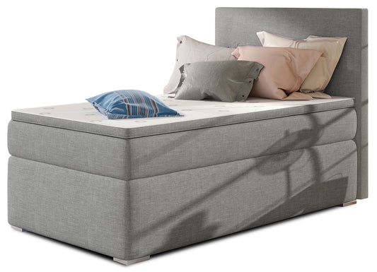 Łóżko kontynentalne Rocco w kolorze Sawana 21 szary, układ prawy – widok studyjny z przodu, prezentujące tapicerowane wykończenie w eleganckim, szarym odcieniu oraz nowoczesny, prosty zagłówek.