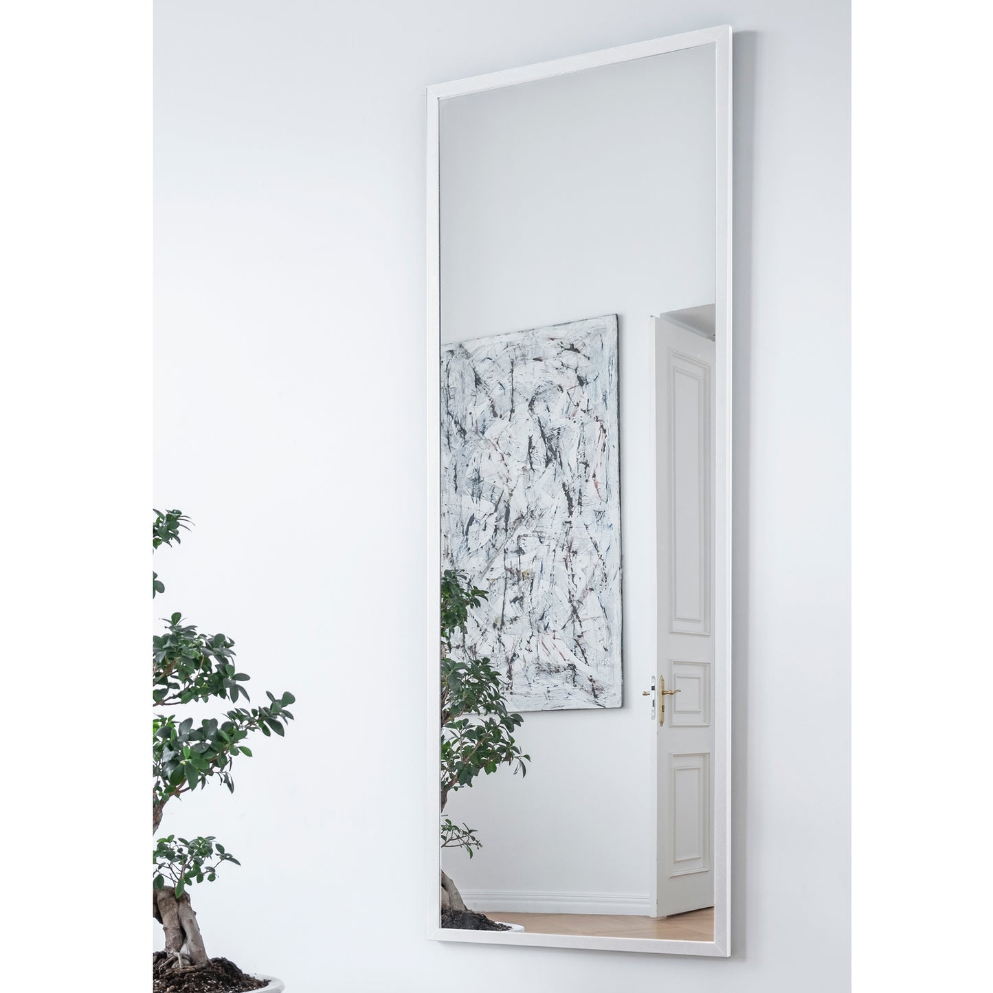 Lustro Aruba w kolorze białym – aranżacja we wnętrzu nowoczesnym – wysokie prostokątne lustro w białej ramie umieszczone na ścianie w salonie z dekoracjami i obrazem.