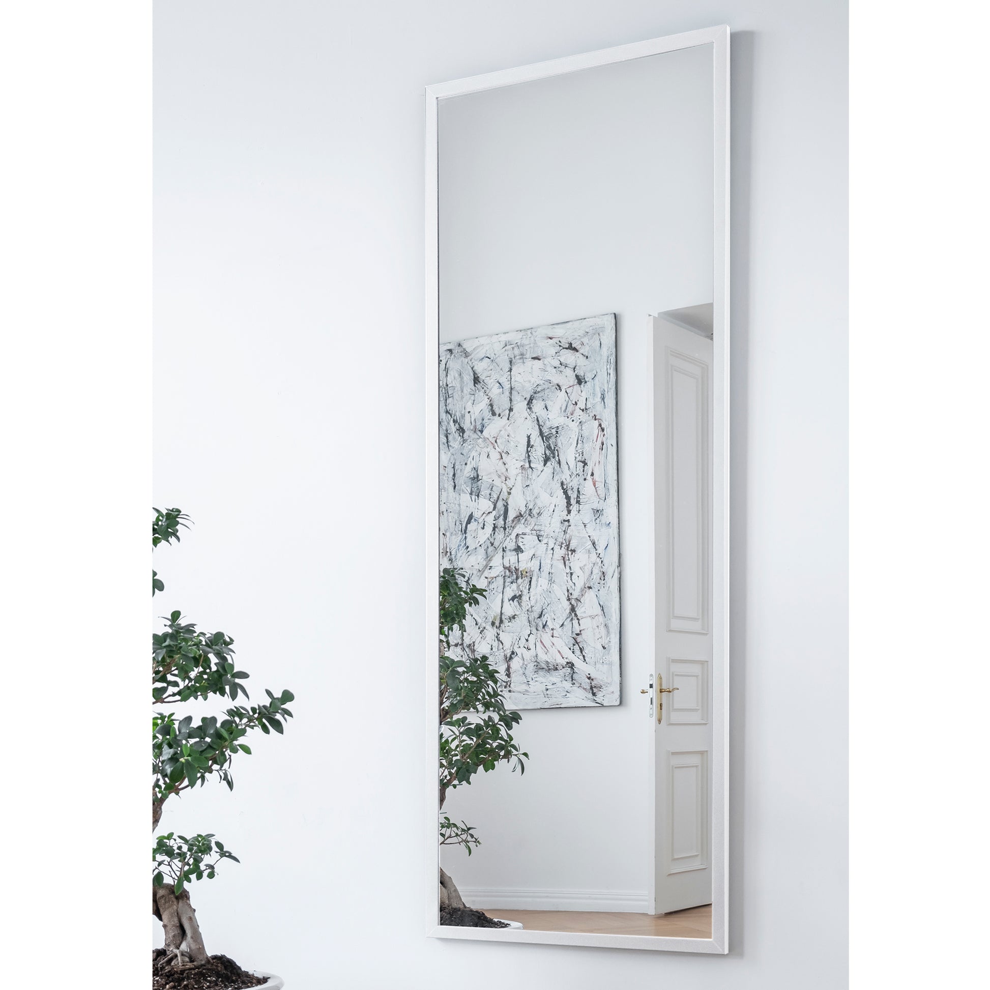 Lustro Aruba w kolorze białym – aranżacja we wnętrzu nowoczesnym – wysokie prostokątne lustro w białej ramie umieszczone na ścianie w salonie z dekoracjami i obrazem.