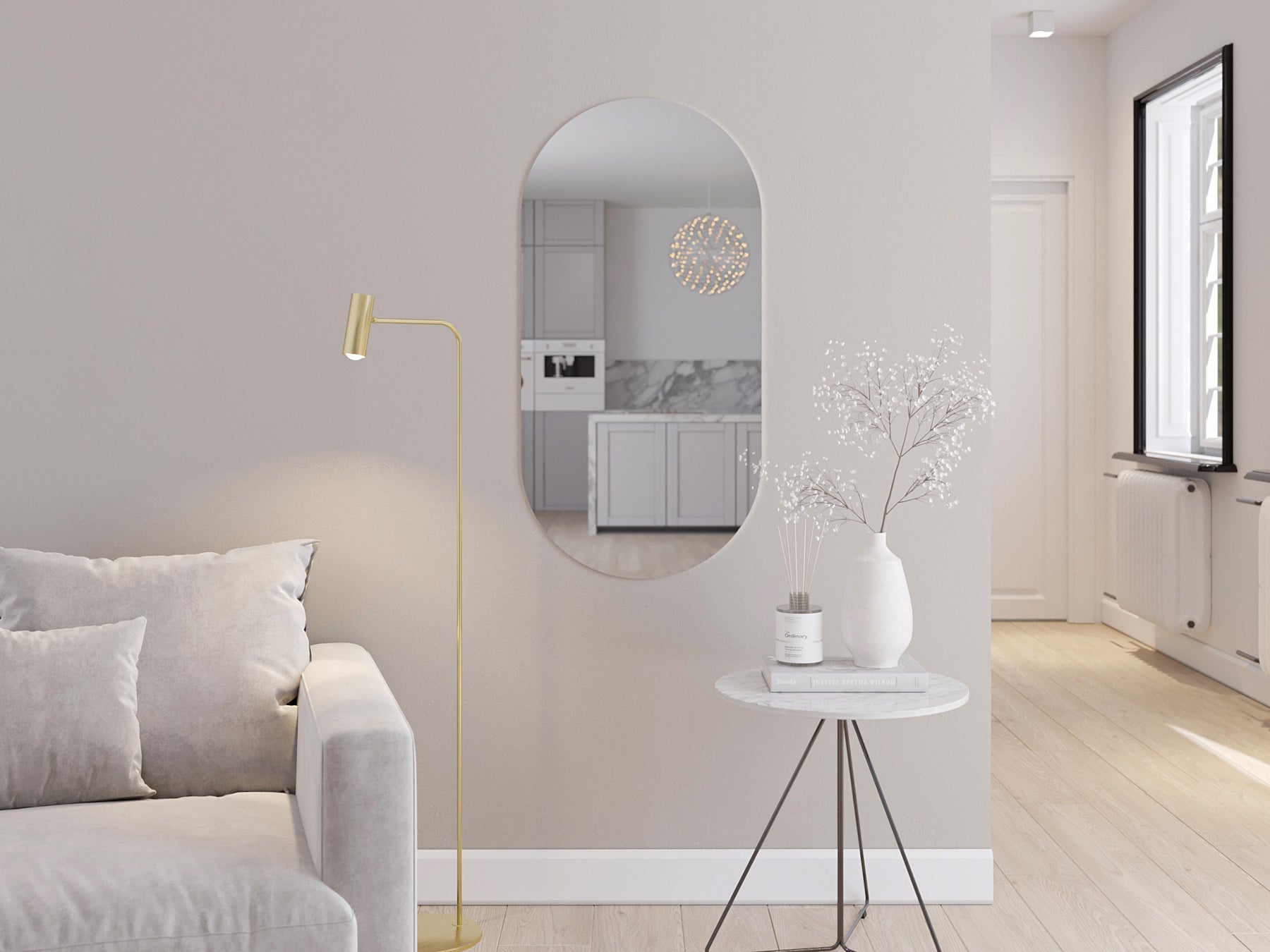 Białe owalne lustro Nunisse 50×100 cm zawieszone na ścianie nad okrągłym stolikiem obok jasnoszarej sofy.
