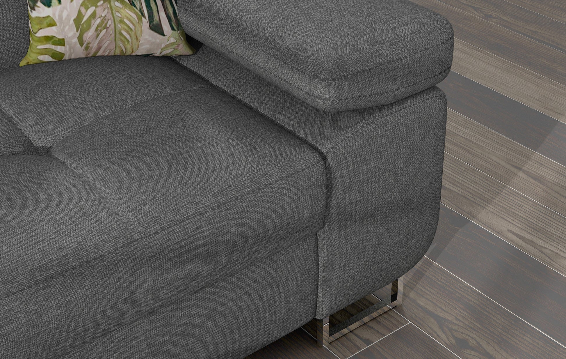 Zbliżenie na podłokietnik narożnika Armando w tkaninie Cover 83 szary z poduszką w roślinny wzór Jungle 37.
