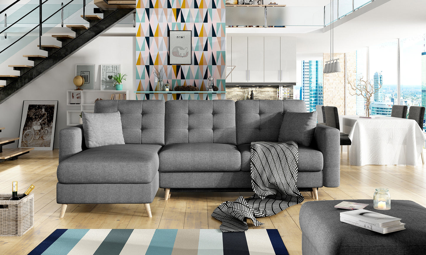 Ciemnoszary narożnik Asgard L w nowoczesnym salonie z kolorową tapetą geometryczną, pledem i minimalistycznym wystrojem wnętrza.