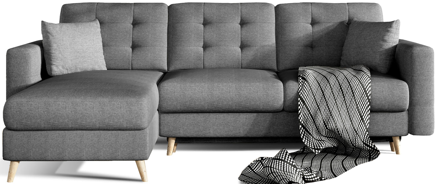 Narożnik Asgard L w kolorze Sawana 05 ciemnoszary, uniwersalny układ, widok frontowy na białym tle z dekoracyjnym pledem i poduszkami.