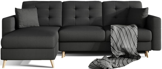 Narożnik Asgard L w czarnej tkaninie Sawana 14 z dekoracyjnym kocem i poduszkami – ujęcie studyjne na białym tle.