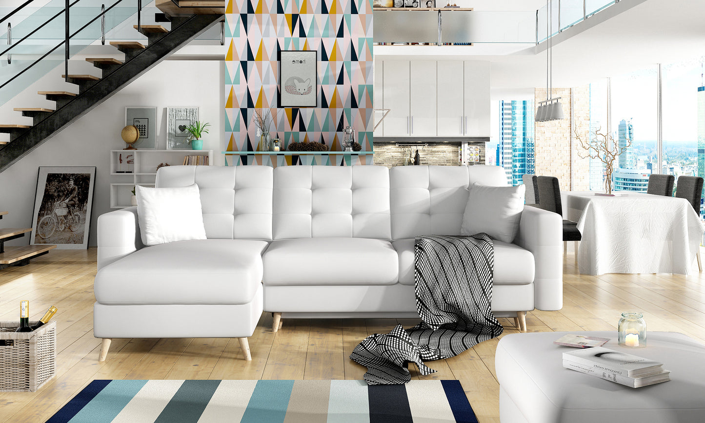 Stylowy narożnik Asgard L w kolorze białym Soft 17 ustawiony w nowoczesnym salonie z drewnianą podłogą, kolorowym dywanem i geometryczną ścianą.