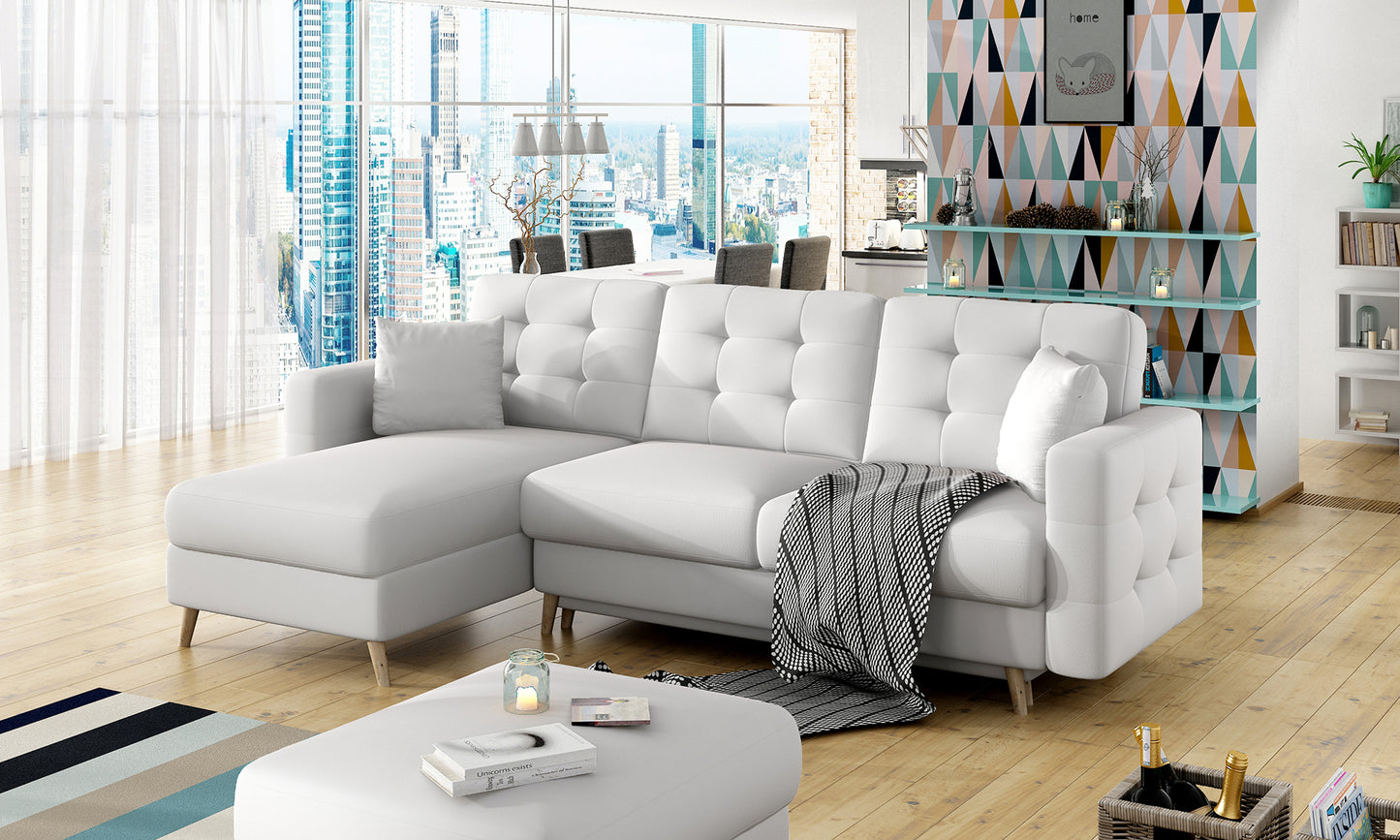 Biały narożnik Asgard L Soft 17 w aranżacji salonu z dużymi oknami, widokiem na miasto i pastelową dekoracją ścienną w tle.