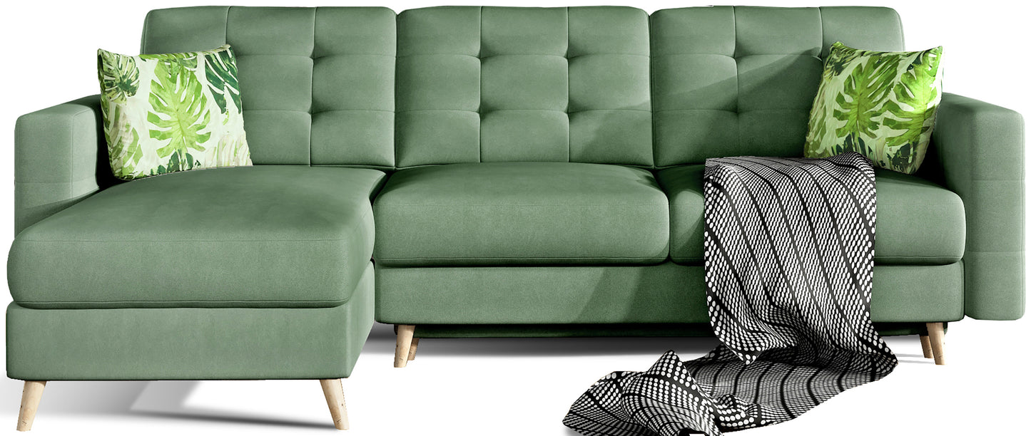 Narożnik Asgard L w kolorze jasnozielonym Soro 34 z poduszkami Jungle 32, widok z przodu na białym tle, z dekoracyjnym kocem i drewnianymi nogami.