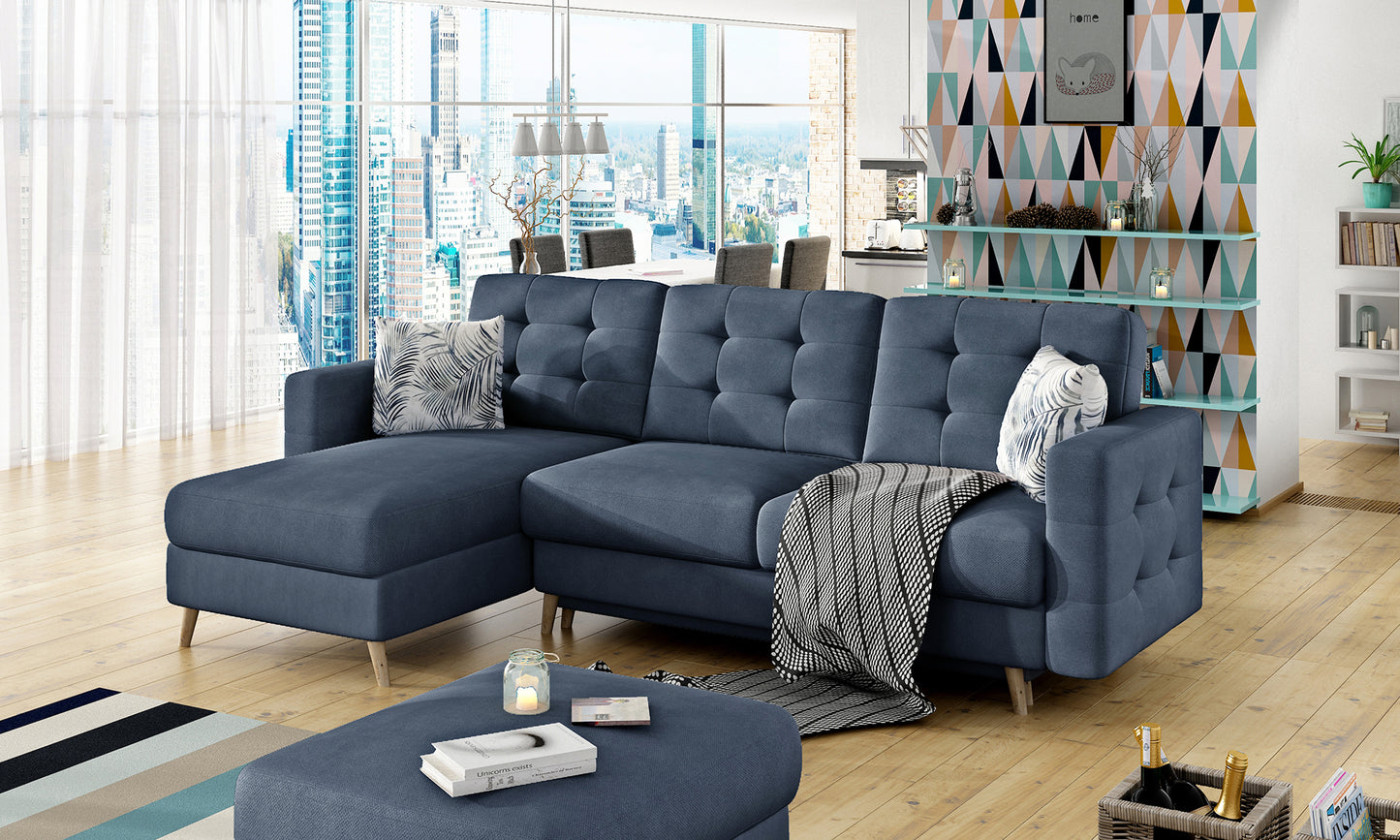 Kątowy widok granatowego narożnika Asgard L z miękkimi poduszkami i stylowym wystrojem w jasnym apartamencie.