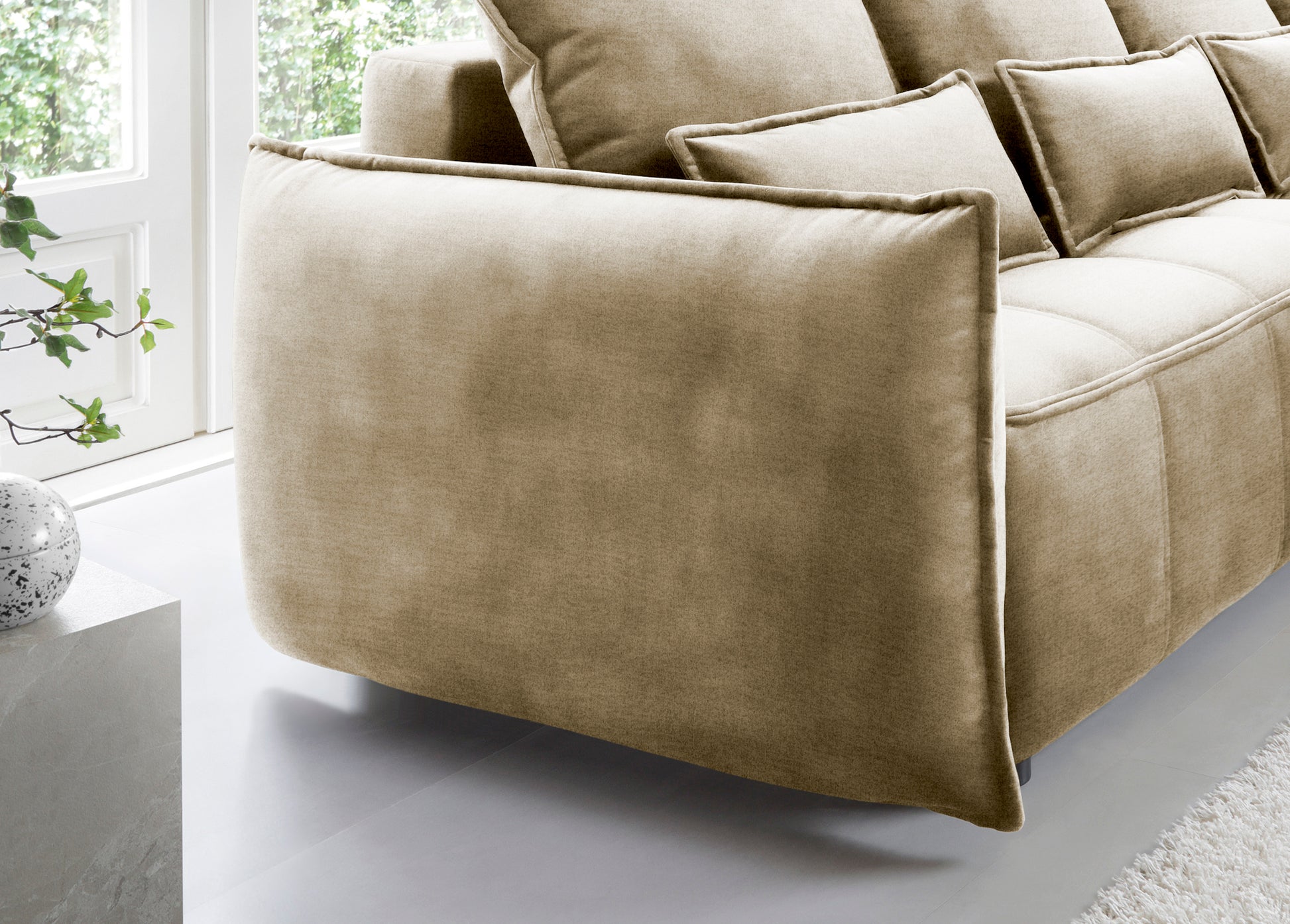 Detal zaokrąglonego podłokietnika i tylnej części narożnika Campo w układzie prawym, tkanina Nube 04 szary na tle okna.