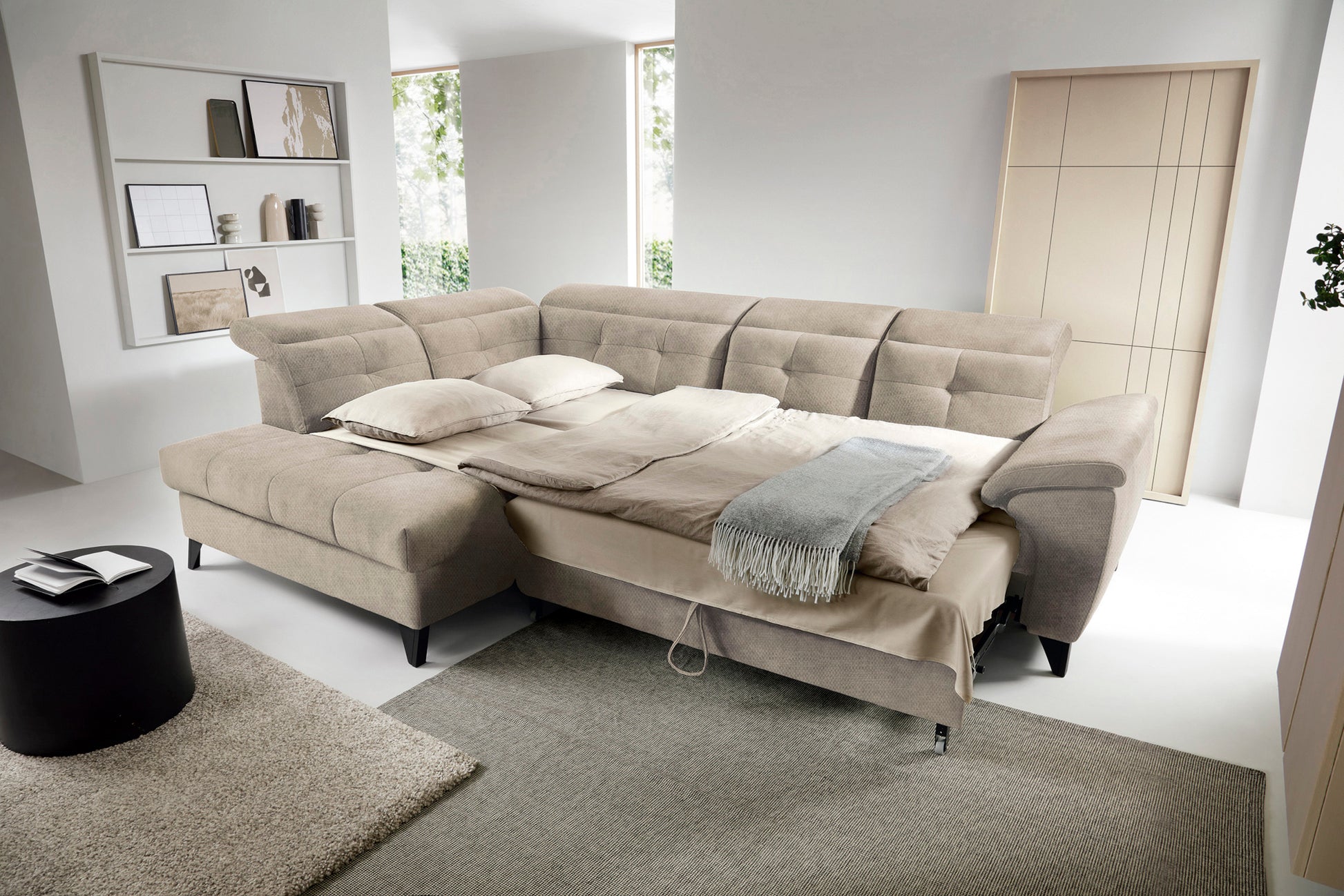 Narożnik Inferne Raquel 20 beżowy w układzie lewym rozłożony jako łóżko, z pościelą i oparciami przestawionymi do spania.