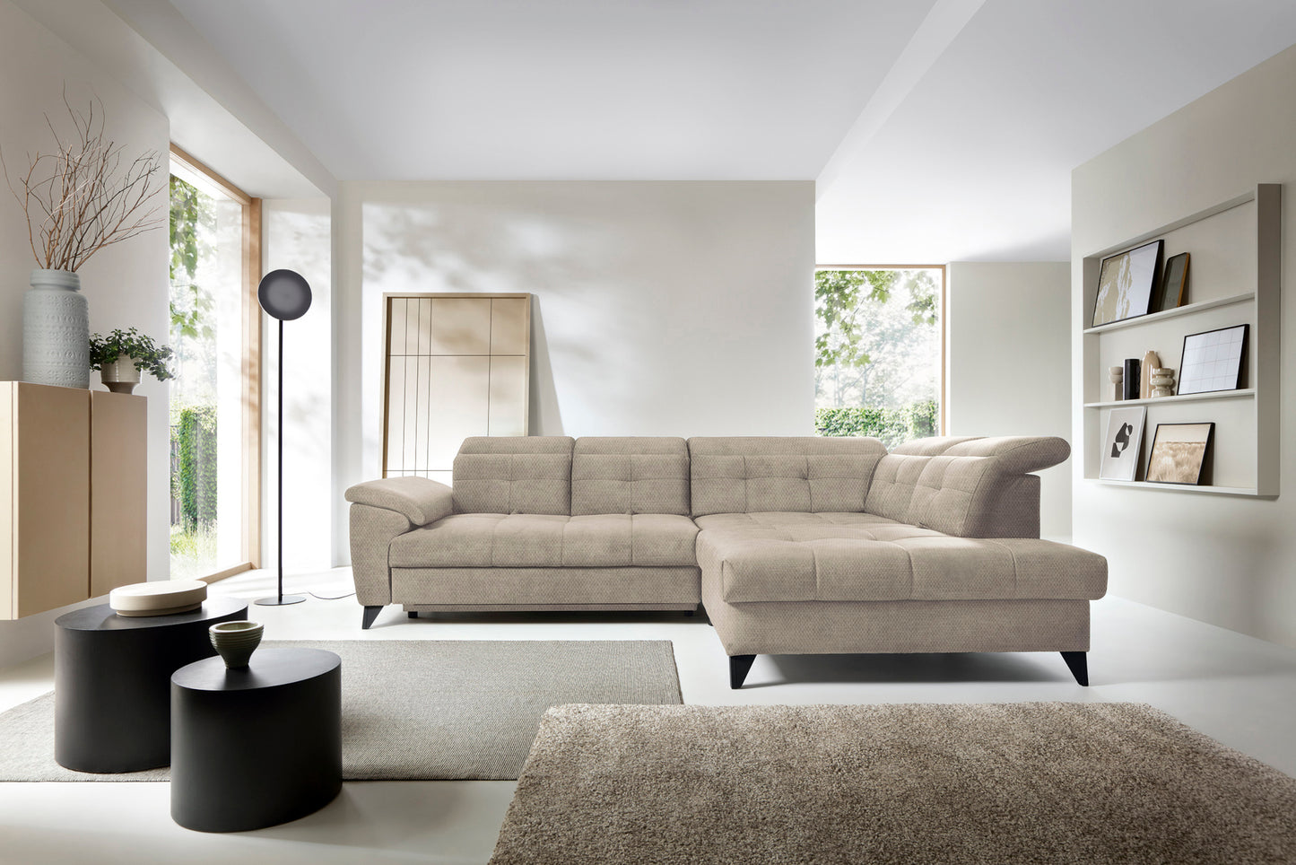 Narożnik Inferne Raquel 20 beżowy w układzie prawym ustawiony w nowoczesnym wnętrzu obok czarnych stolików i lampy stojącej.