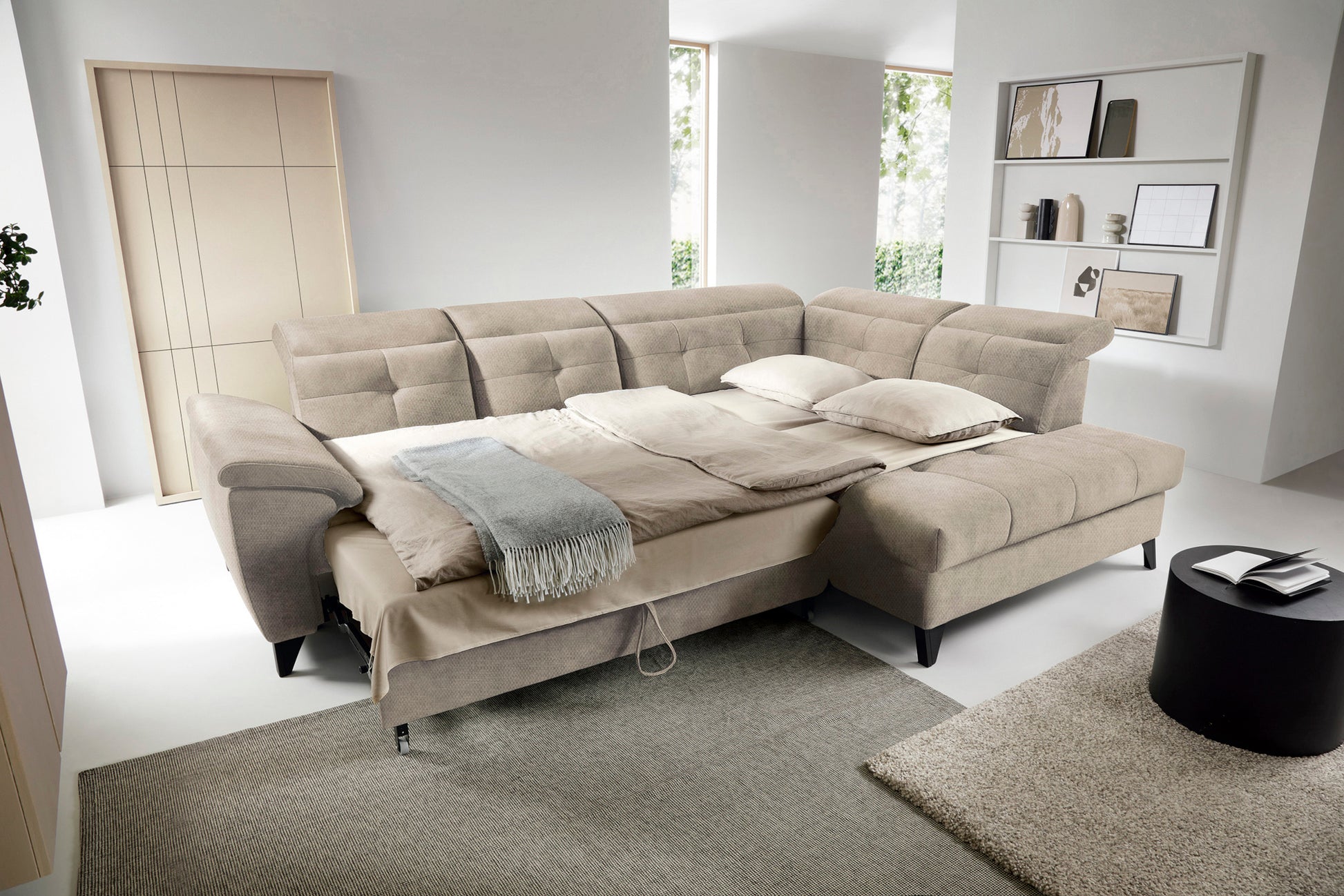Narożnik Inferne Raquel 20 beżowy w układzie prawym rozłożony jako łóżko, z pościelą i oparciami przestawionymi do spania.