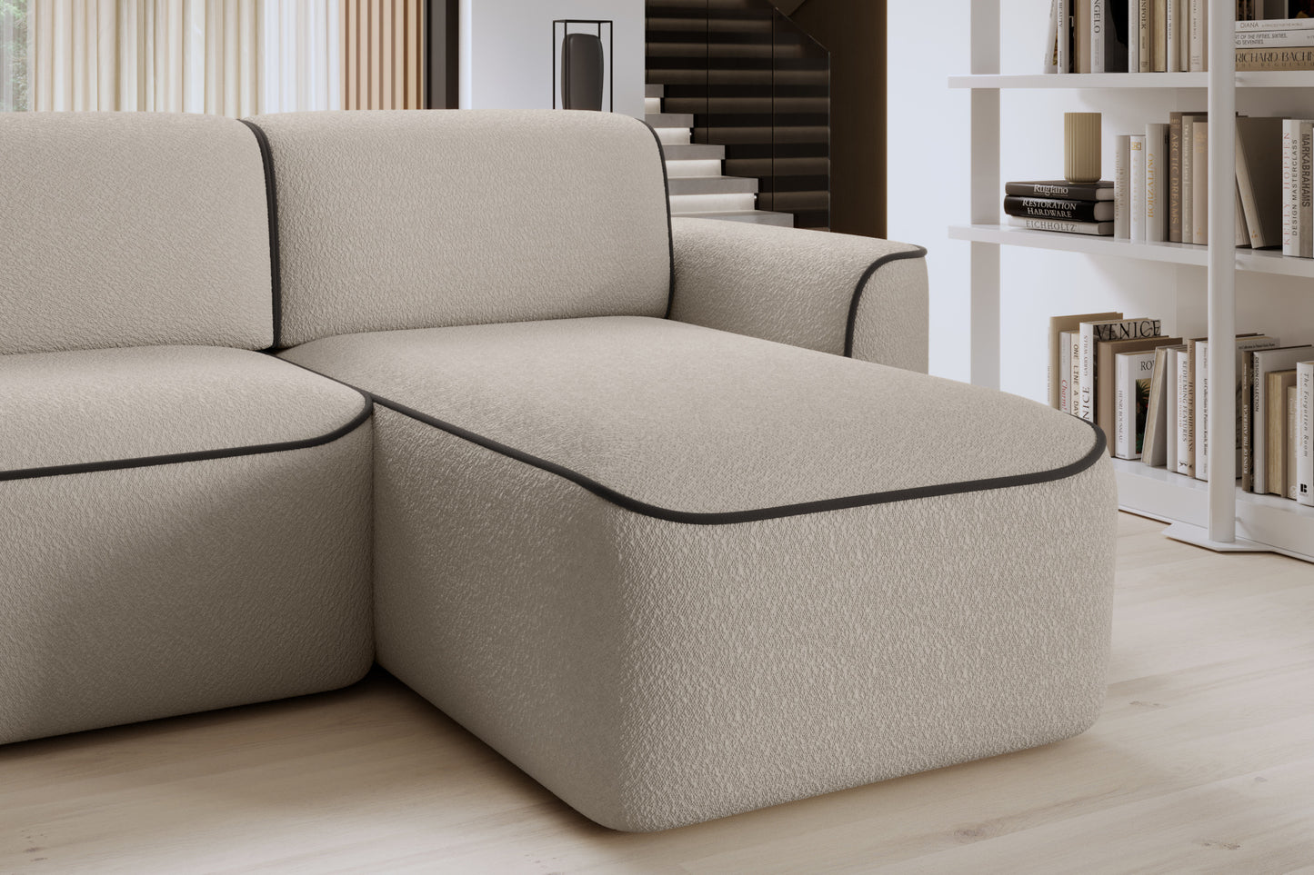 Zbliżenie przedniej krawędzi szezlongu po prawej stronie narożnika Ume, miękka tapicerka Royal 18 beżowy obwiedziona elegancką lamówką w kolorze brązu.