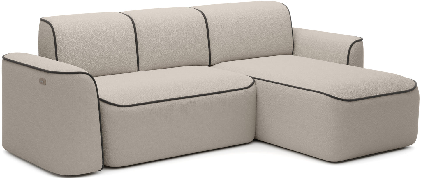 Ukosny widok narożnika Ume w układzie prawym, wyraźnie zaznaczony szezlong po prawej stronie i subtelna lamówka Velvetmat 22 brązowy na beżowym bouclé.