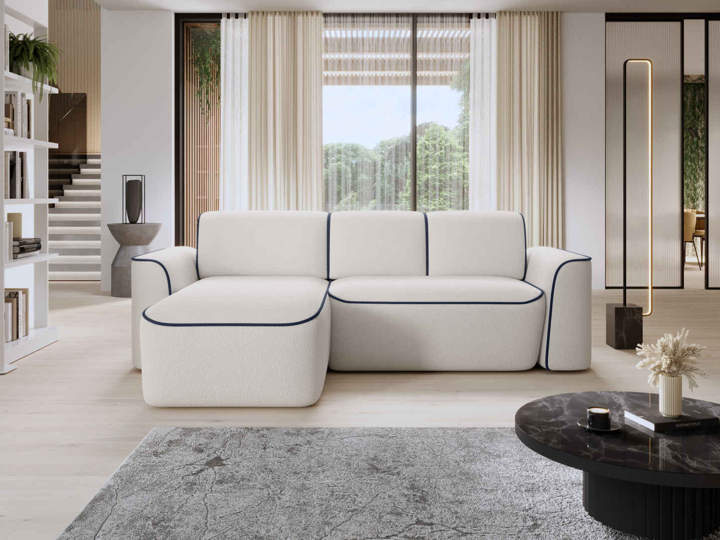 Narożnik Ume lewostronny z otomanką we wnętrzu salonu z dużym oknem, jasną drewnianą podłogą i granatową lamówką na białej tkaninie.