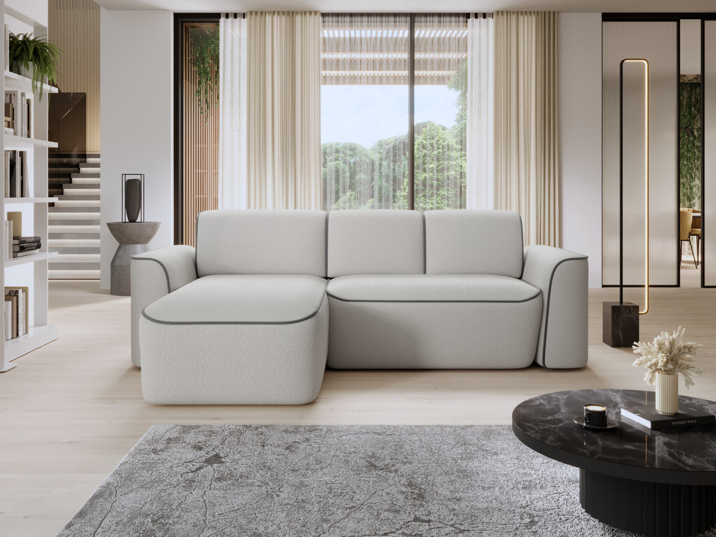 Narożnik Ume z lewą otomanką we wnętrzu salonu przy dużym oknie i jasnej drewnianej podłodze, biała tkanina bouclé z subtelną szarą obwódką.