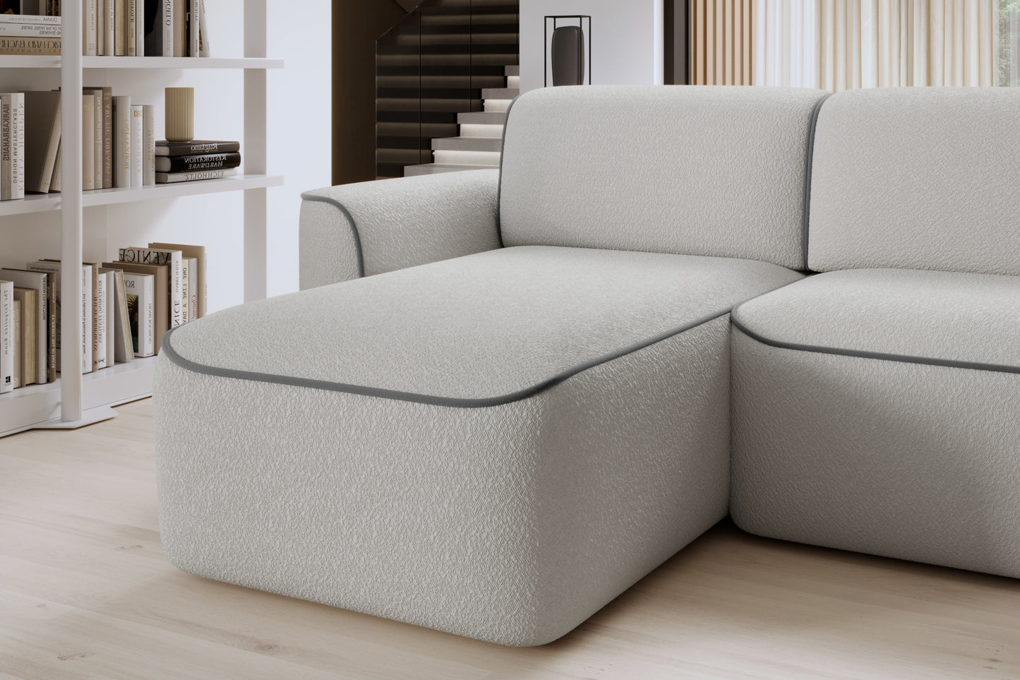 Zbliżenie przedniego narożnika otomanki Ume w układzie lewym, biała tkanina Royal 03 i obwódka Velvetmat 04 szary.