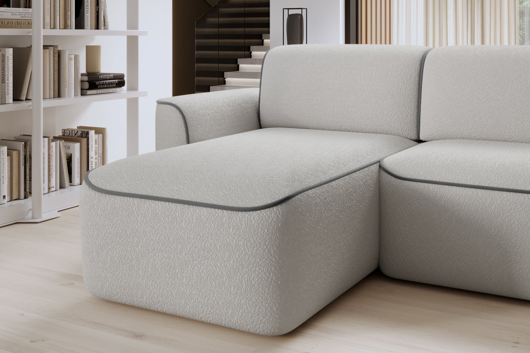 Zbliżenie przedniego narożnika otomanki Ume w układzie lewym, biała tkanina Royal 03 i obwódka Velvetmat 04 szary.