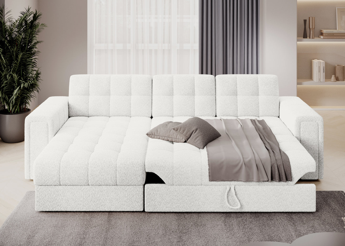 Rozłożona sofa narożna Royal 01 biały z funkcją spania, dekoracyjną narzutą i poduszkami w nowoczesnym salonie z zasłonami.