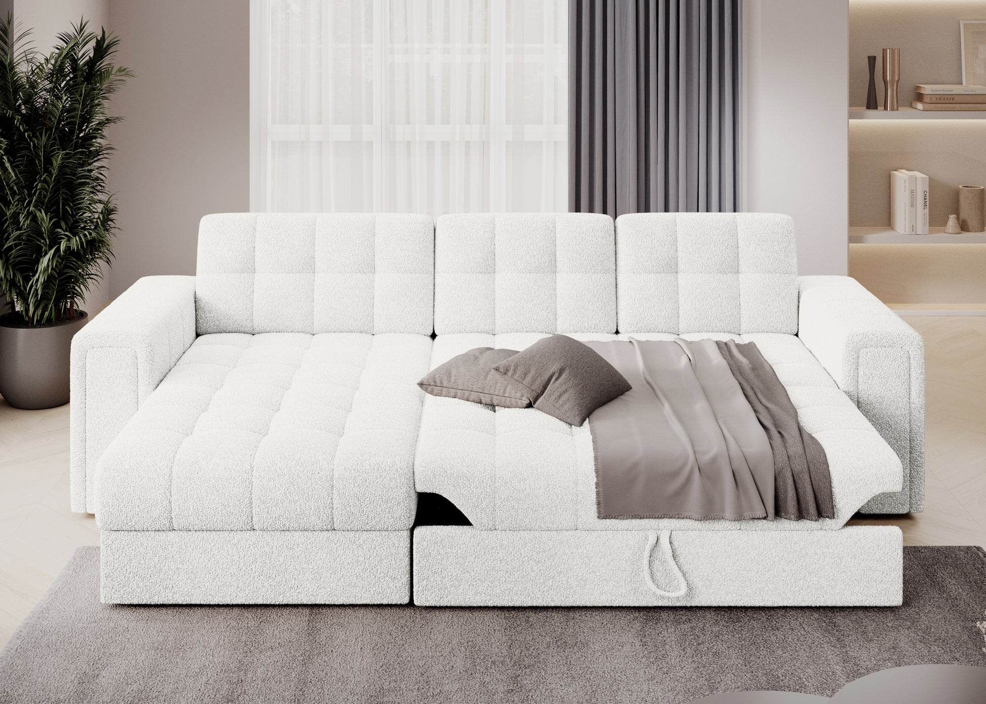 Rozłożona sofa narożna Royal 01 biały z funkcją spania, dekoracyjną narzutą i poduszkami w nowoczesnym salonie z zasłonami.