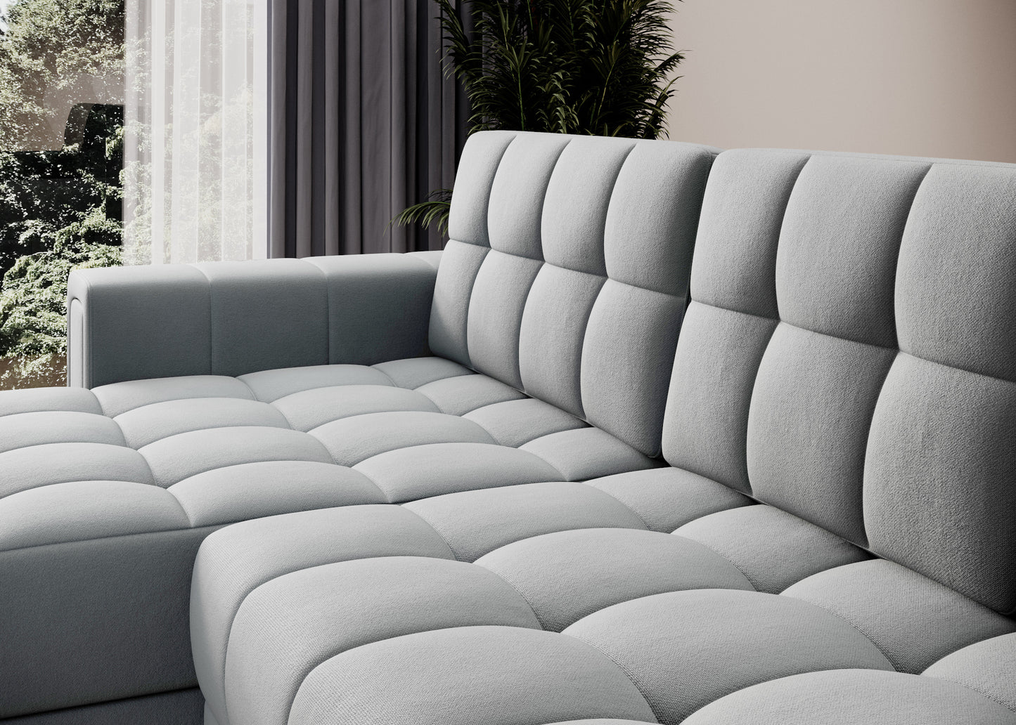 Zbliżenie na pikowaną tapicerkę szarej sofy narożnej – miękkie siedzisko i oparcie w nowoczesnym wnętrzu z zasłonami i roślinnością.