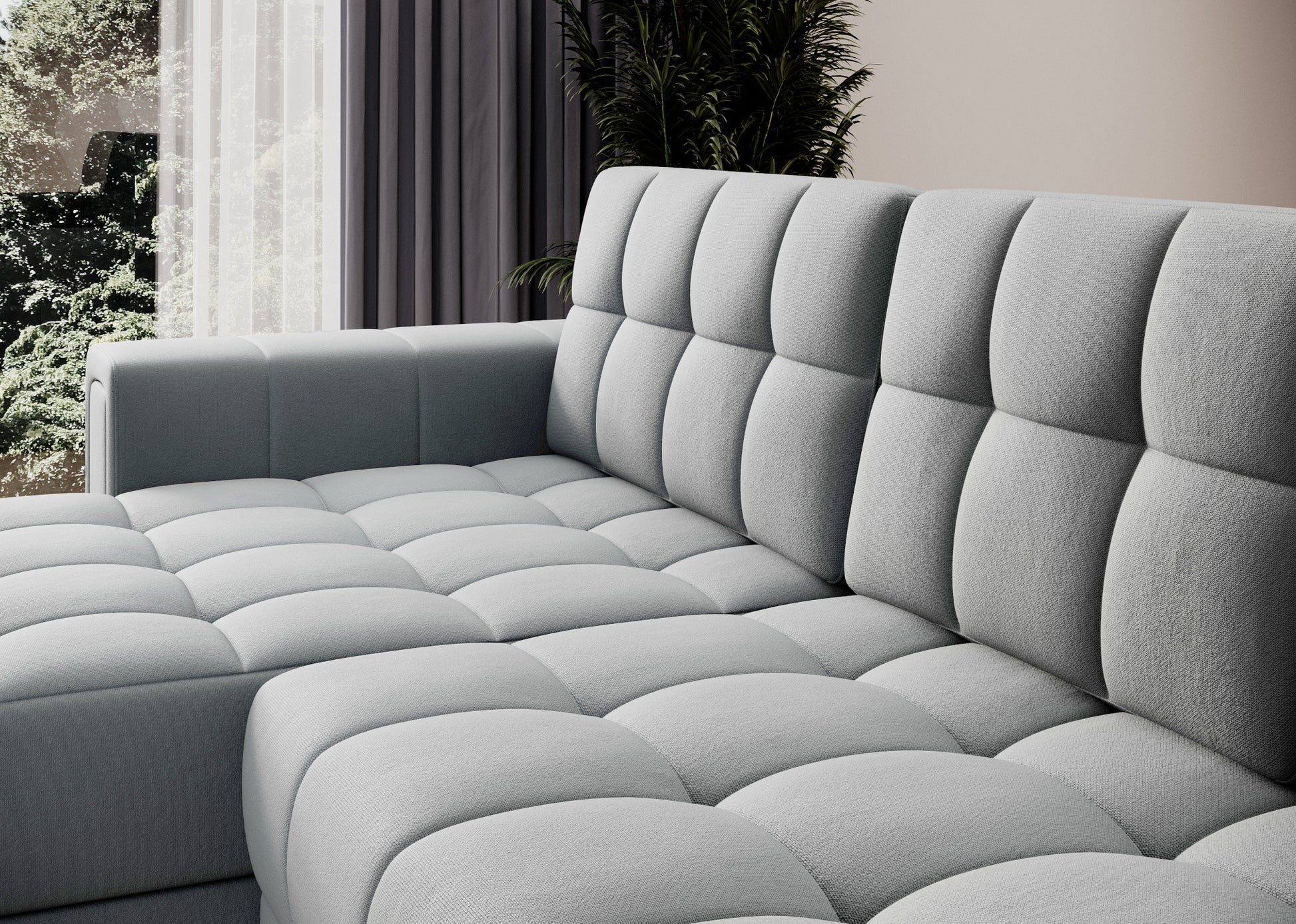 Zbliżenie na pikowaną tapicerkę szarej sofy narożnej – miękkie siedzisko i oparcie w nowoczesnym wnętrzu z zasłonami i roślinnością.
