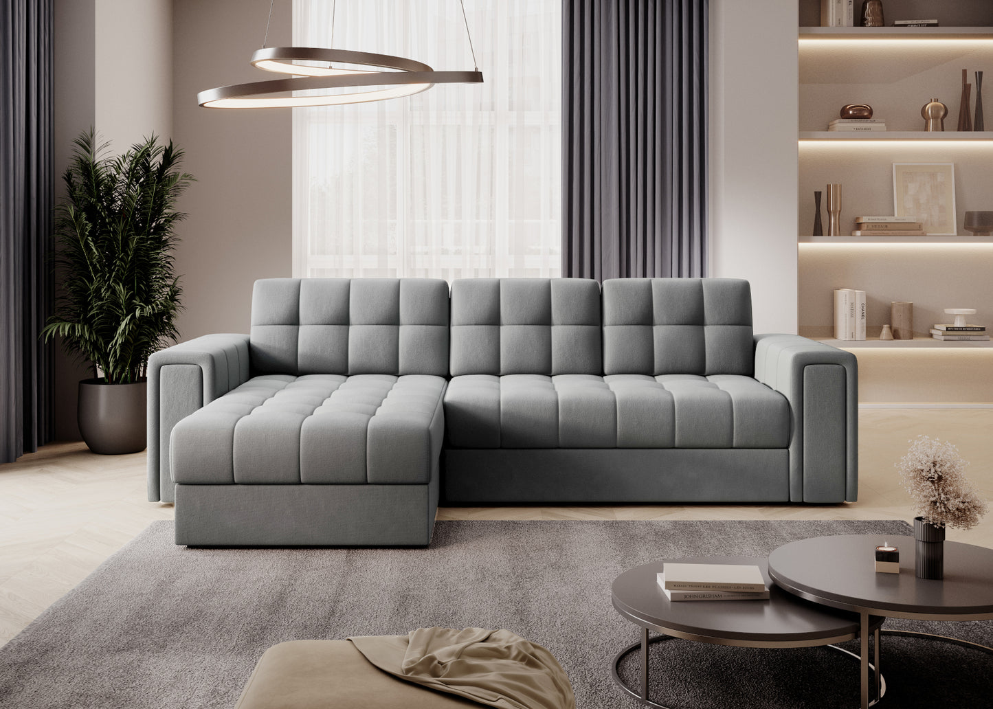 Szara sofa narożna z pikowanym siedziskiem i oparciem, nowoczesny salon z regałem, zasłonami i okrągłymi stolikami kawowymi.