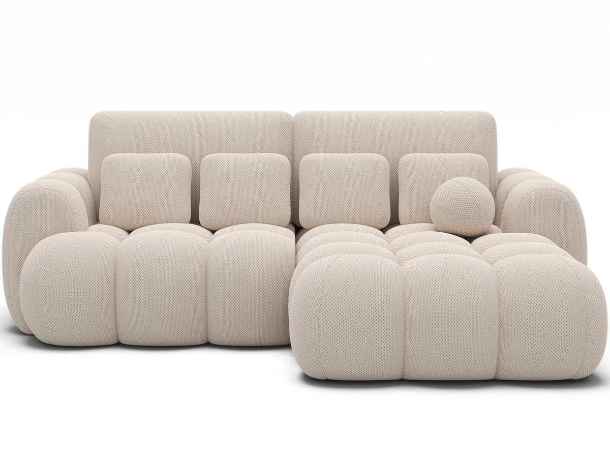 Narożnik Covelion prawy w tkaninie Calmora 18 kaszmir kremowy, ujęcie na wprost pokazujące szerokie siedzisko i miękką obłą bryłę