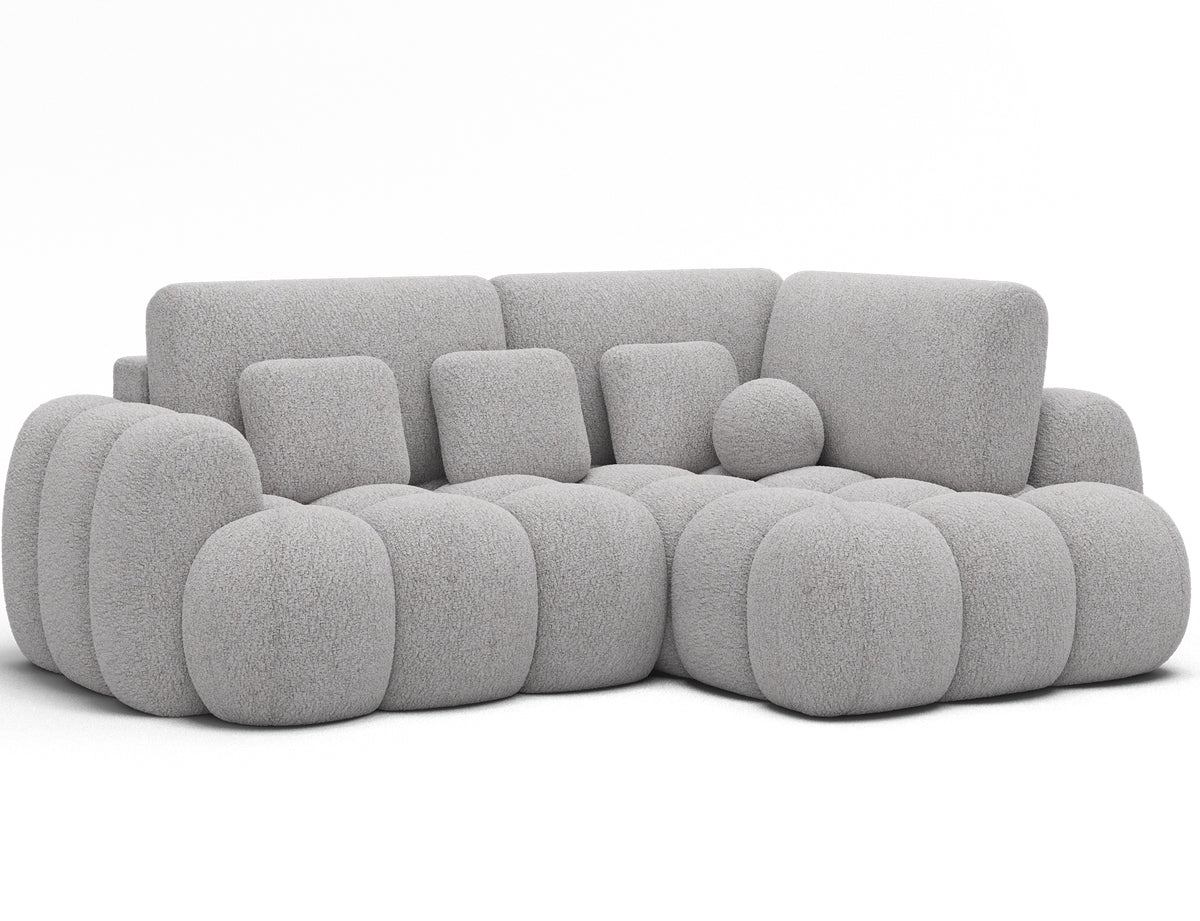 Narożnik Cozion prawy szary, ujęcie pod skosem na białym tle pokazujące obłą bryłę, segmentowe siedzisko i strukturalną tkaninę.