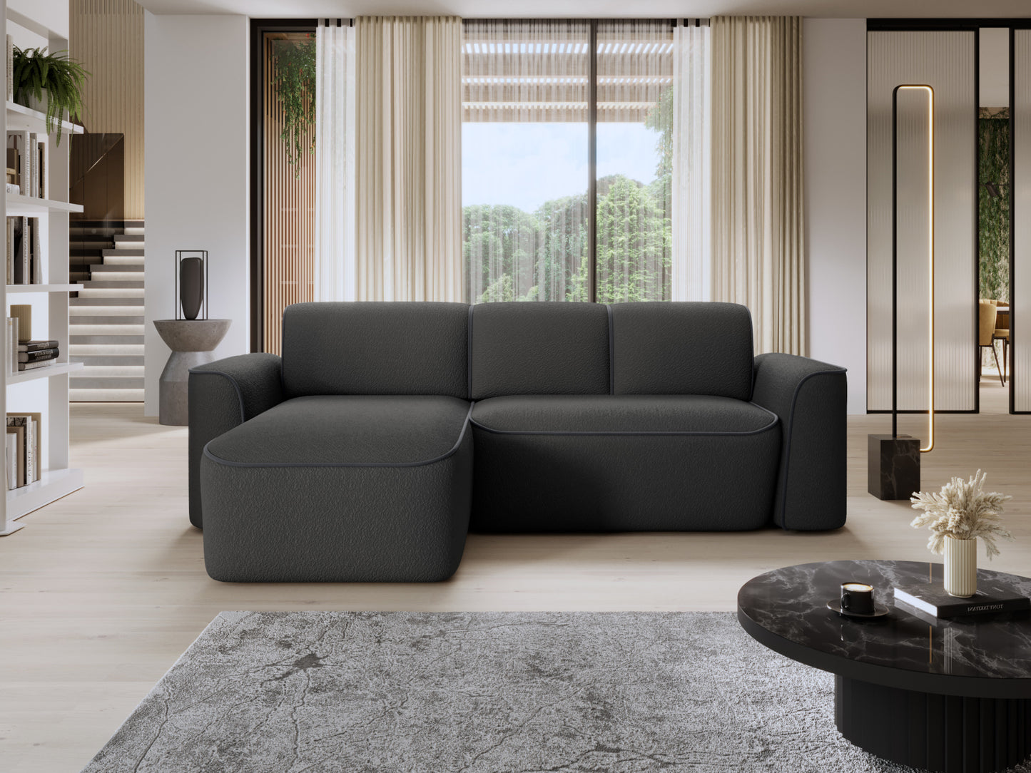 Narożnik Ume w układzie lewym ustawiony w nowoczesnym salonie z dużymi oknami, czarna tkanina bouclé z dyskretną lamówką w odcieniu ciemnoszarym.