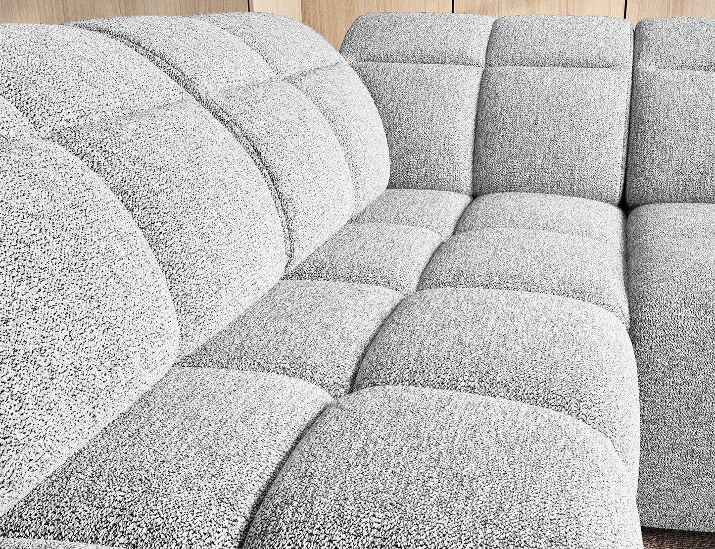 Zbliżenie na siedzisko narożnika Falconn Coralline 01 z miękkiej tkaniny bouclé i wyrazistym pikowaniem modułowym.