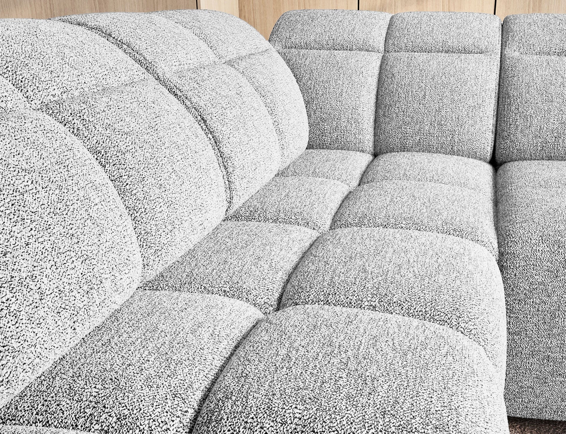 Zbliżenie na siedzisko narożnika Falconn Coralline 01 z miękkiej tkaniny bouclé i wyrazistym pikowaniem modułowym.