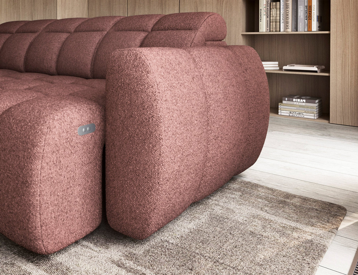 Boczny widok różowego narożnika Falconn Paolli 24 z podłokietnikiem, drewniana podłoga, regał z książkami w tle, jasne wnętrze.