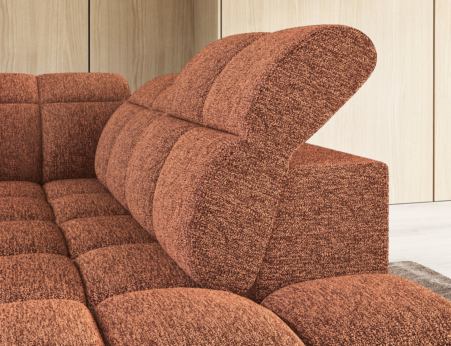 Zbliżenie na regulowane oparcie narożnika Falconn z wyprofilowanym zagłówkiem w kolorze ceglastym.