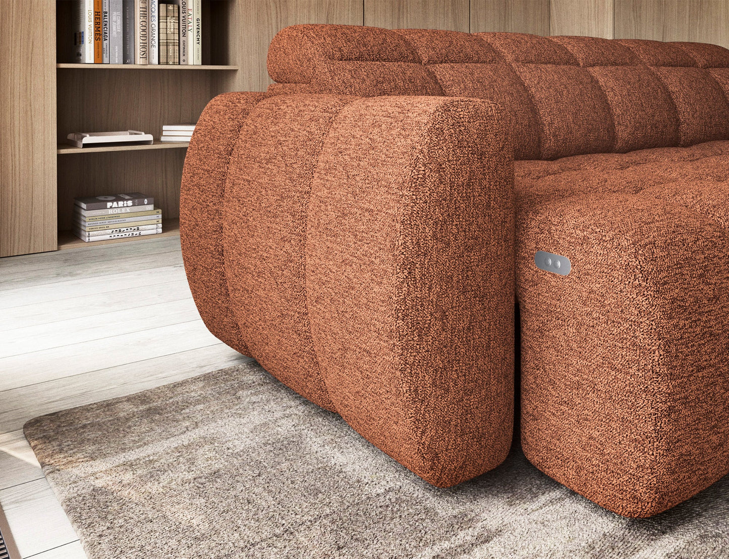 Zbliżenie na zaokrąglony podłokietnik narożnika Falconn z tkaniny w kolorze ceglastym, z widocznym panelem sterowania.