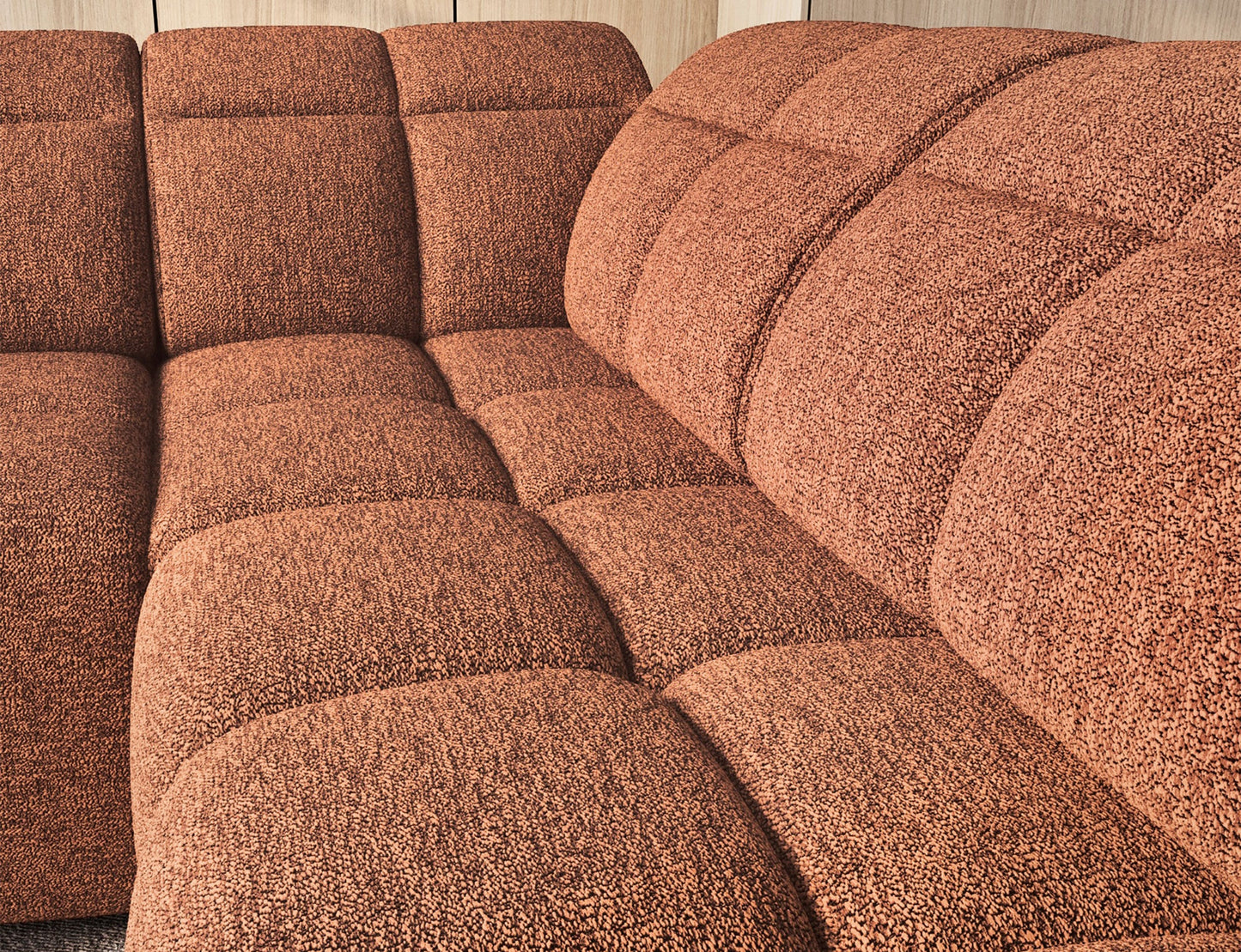 Zbliżenie na siedzisko narożnika Falconn z wyraźnym pikowaniem i miękkim wykończeniem w kolorze ceglastym.