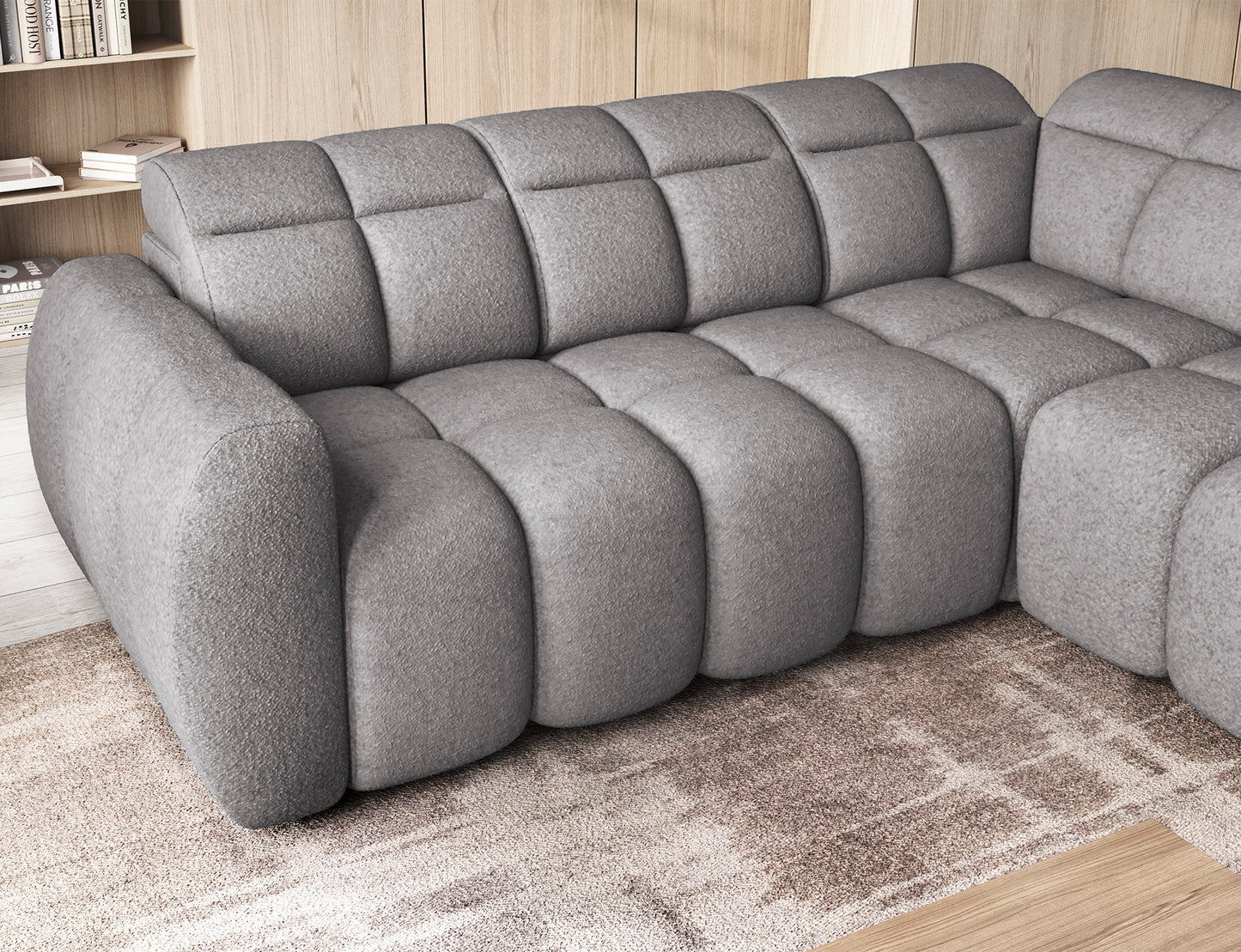 Szary narożnik Falconn w tkaninie Paolli 04 z wsuniętym siedziskiem, widok zbliżeniowy na miękkie pikowane poduszki i podłokietnik, ustawiony w jasnym salonie.