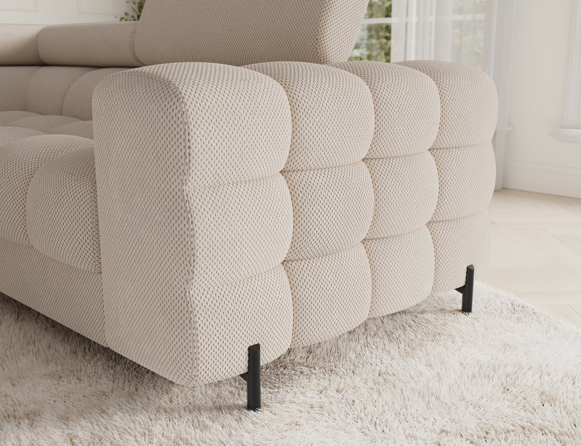 Pikowany bok narożnika Fectory Calmora 18 beżowy z widoczną strukturą tkaniny i czarną, metalową nogą.