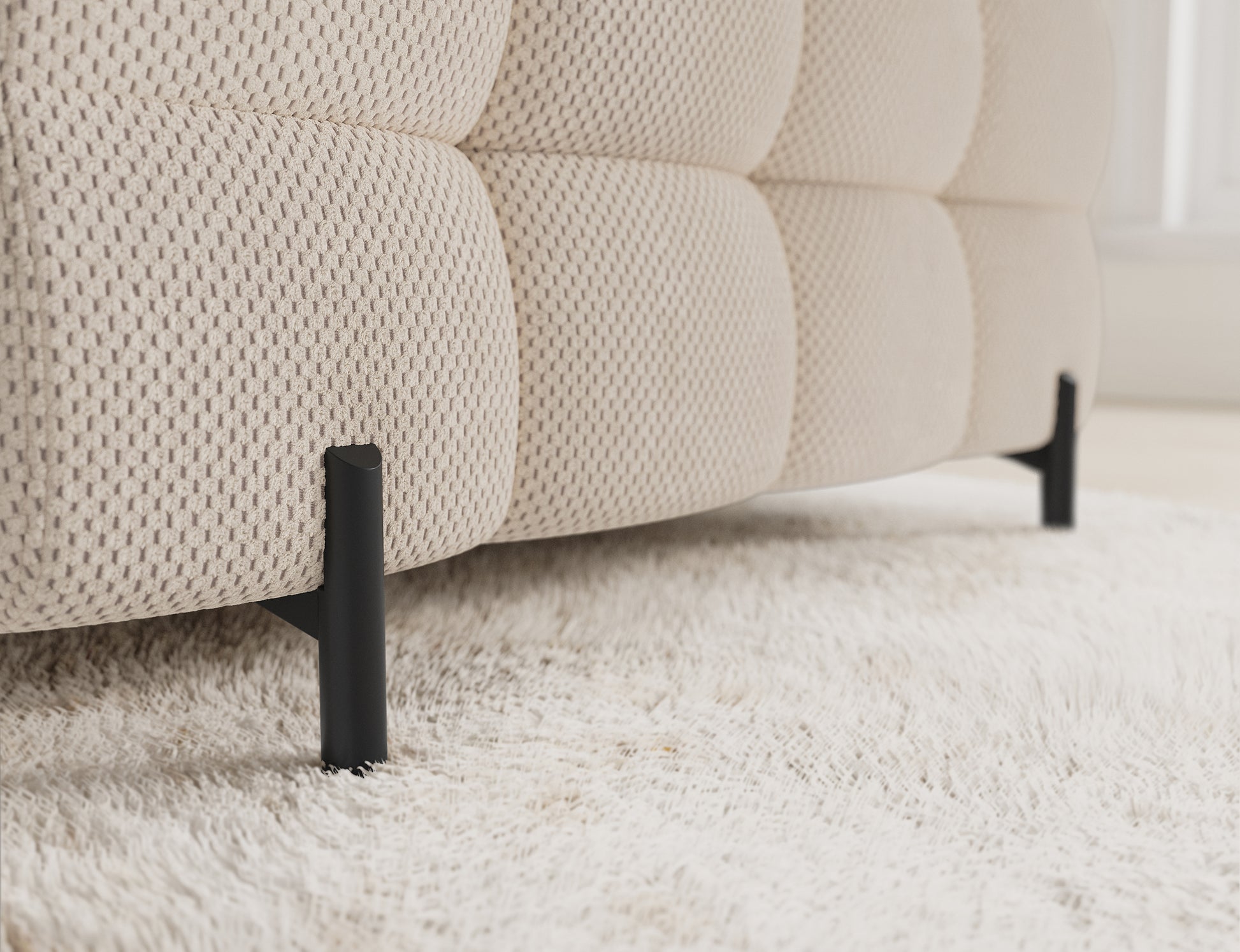 Czarna, metalowa noga narożnika Fectory Calmora 18 beżowy – detal konstrukcyjny na tle jasnego dywanu