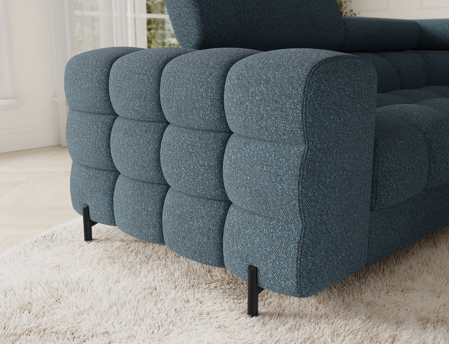 Detal narożnika Fectory w niebieskim kolorze, ukazujący zaokrąglone krawędzie, tapicerowaną powierzchnię i eleganckie metalowe nogi.