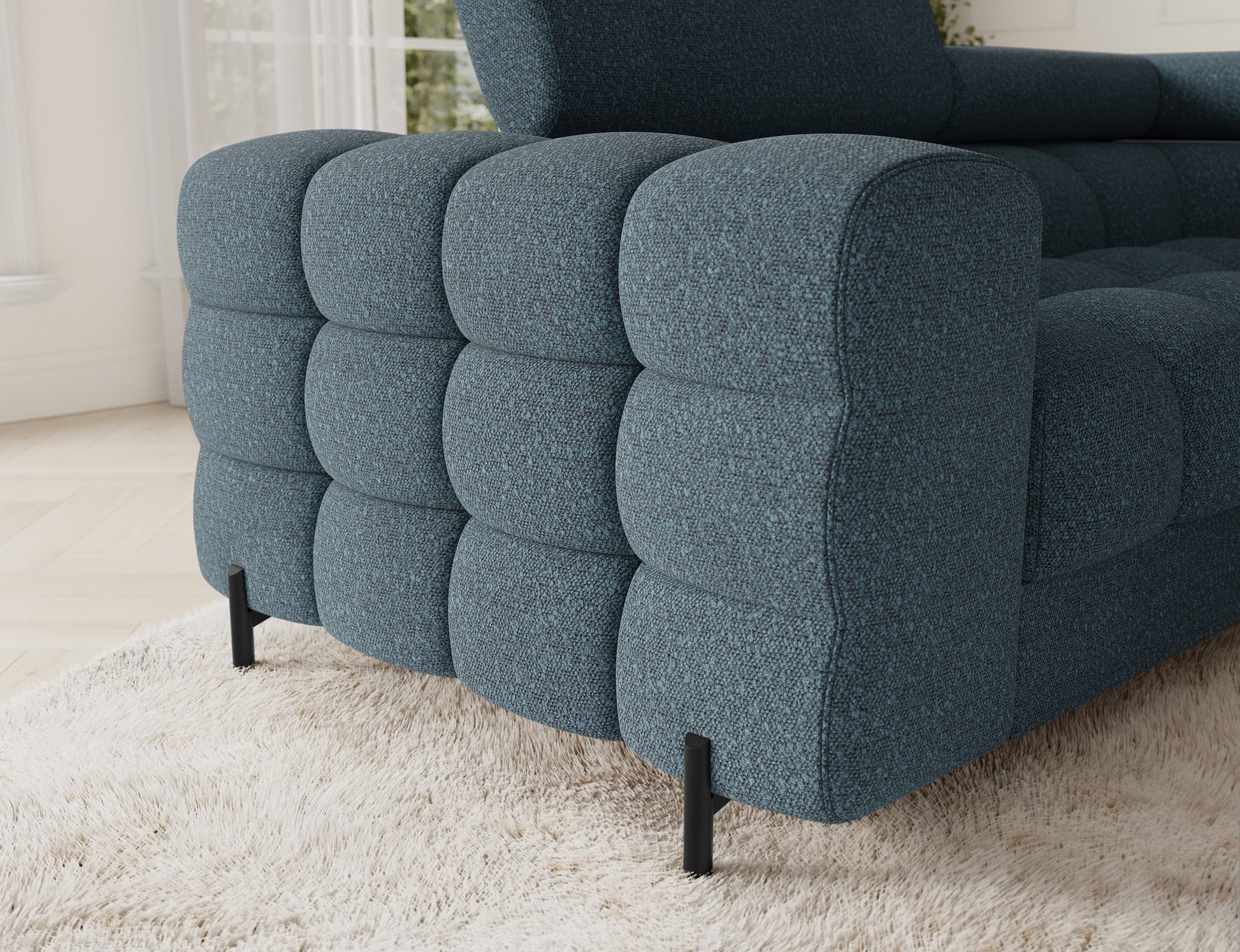 Detal narożnika Fectory w niebieskim kolorze, ukazujący zaokrąglone krawędzie, tapicerowaną powierzchnię i eleganckie metalowe nogi.