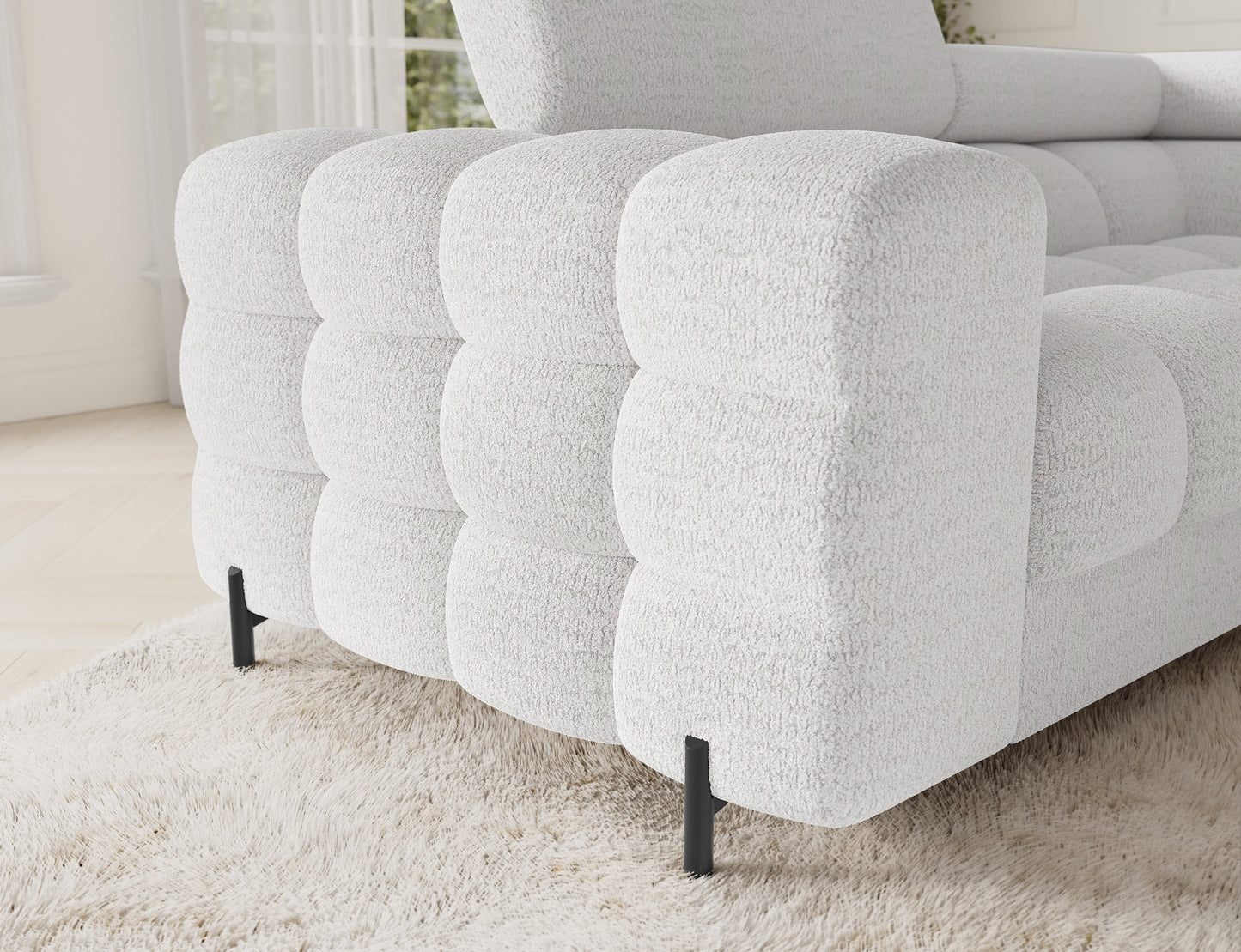 Zbliżenie na lewy narożnik Fectory w białym kolorze, z wyraźnie widocznymi, subtelnymi detalami materiału oraz metalowymi nogami.