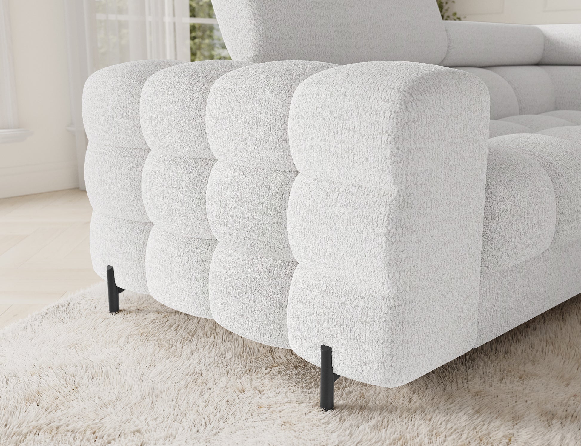 Zbliżenie na lewy narożnik Fectory w białym kolorze, z wyraźnie widocznymi, subtelnymi detalami materiału oraz metalowymi nogami.