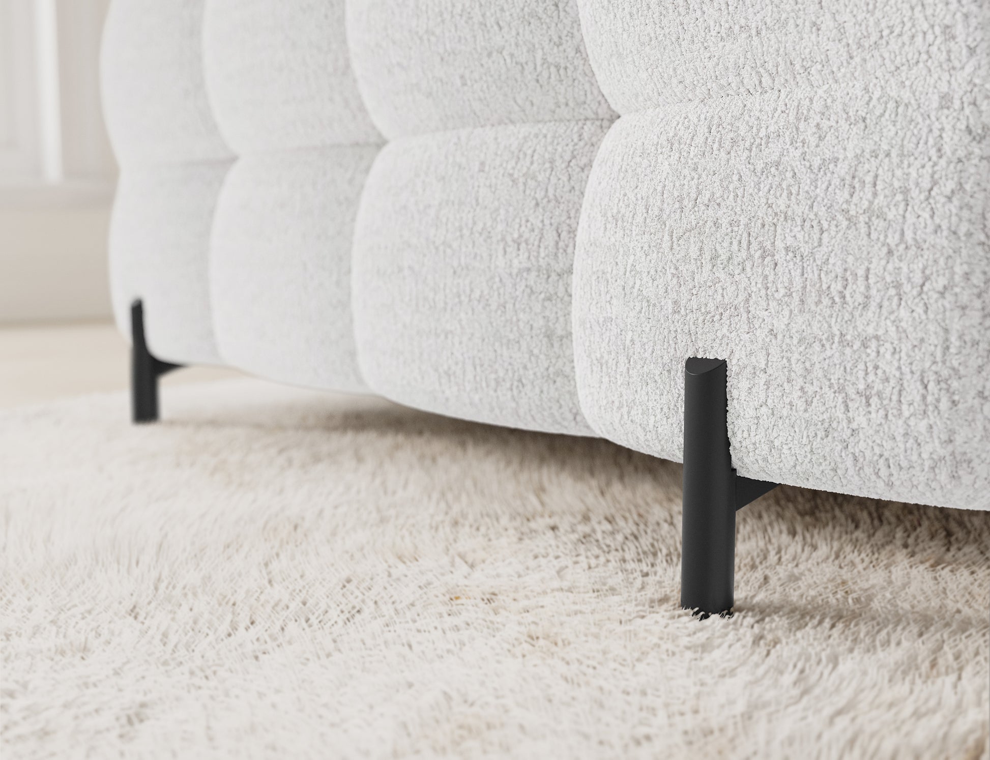 Detalowy widok lewego narożnika Fectory w kolorze białym, z metalowymi nogami i miękkim, przestrzennym siedziskiem.
