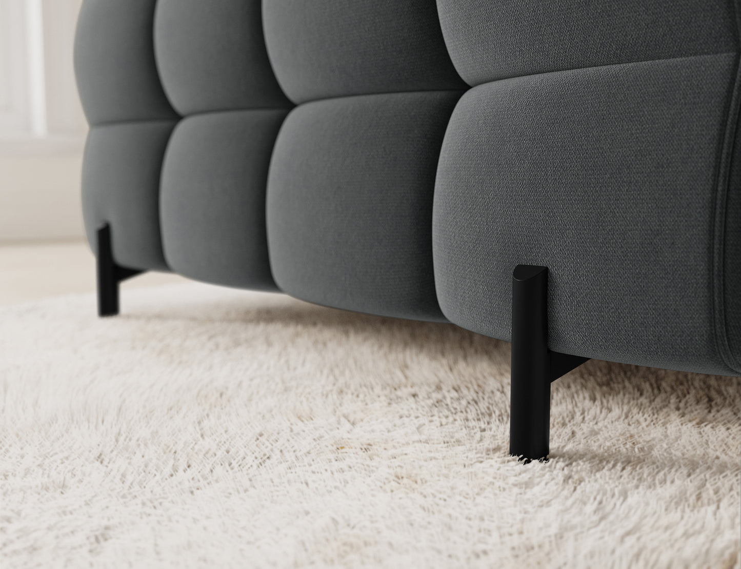 Zbliżenie na narożnik Fectory w tkaninie Sola 06, ukazujące eleganckie pikowanie, a także subtelne metalowe nogi.