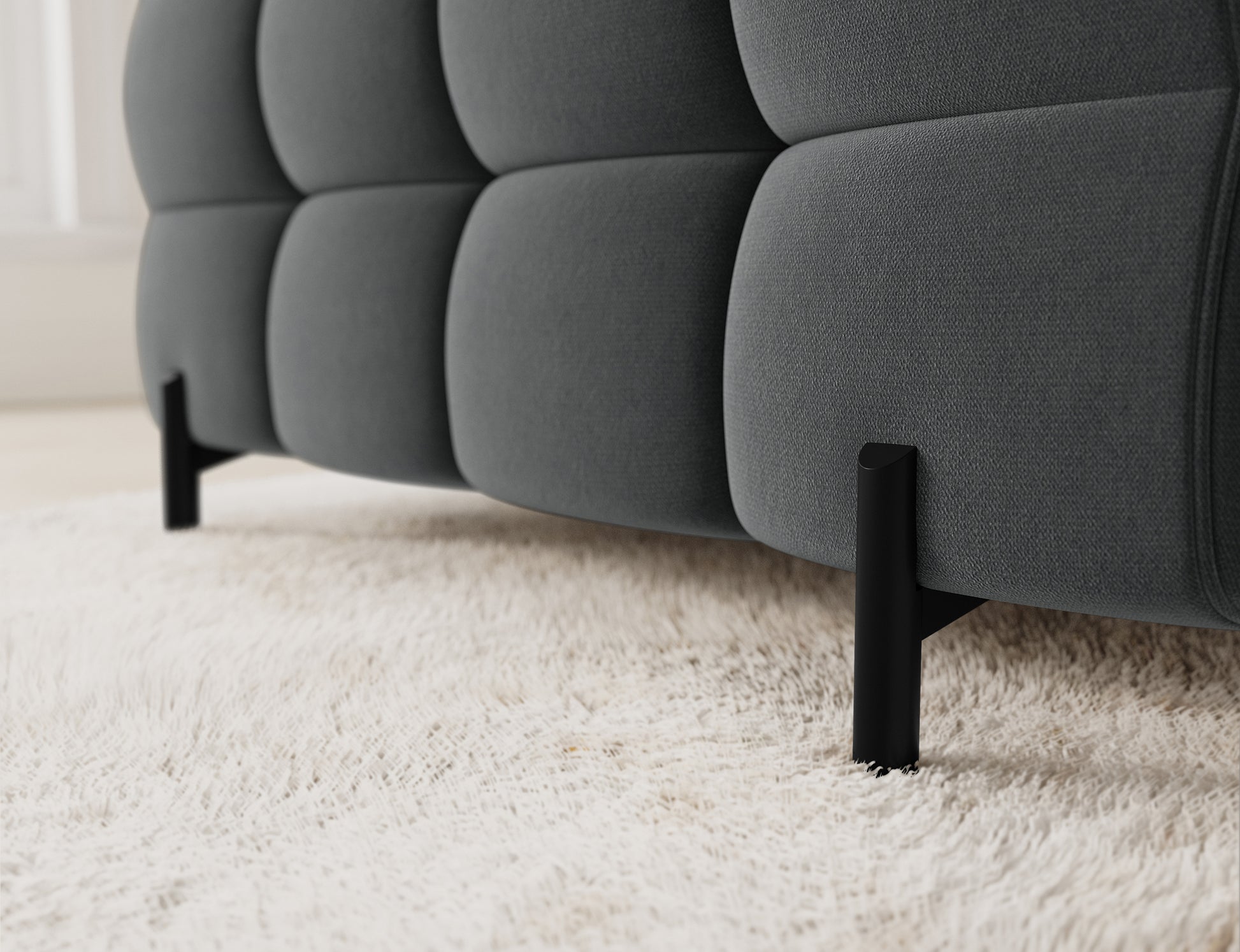 Zbliżenie na narożnik Fectory w tkaninie Sola 06, ukazujące eleganckie pikowanie, a także subtelne metalowe nogi.