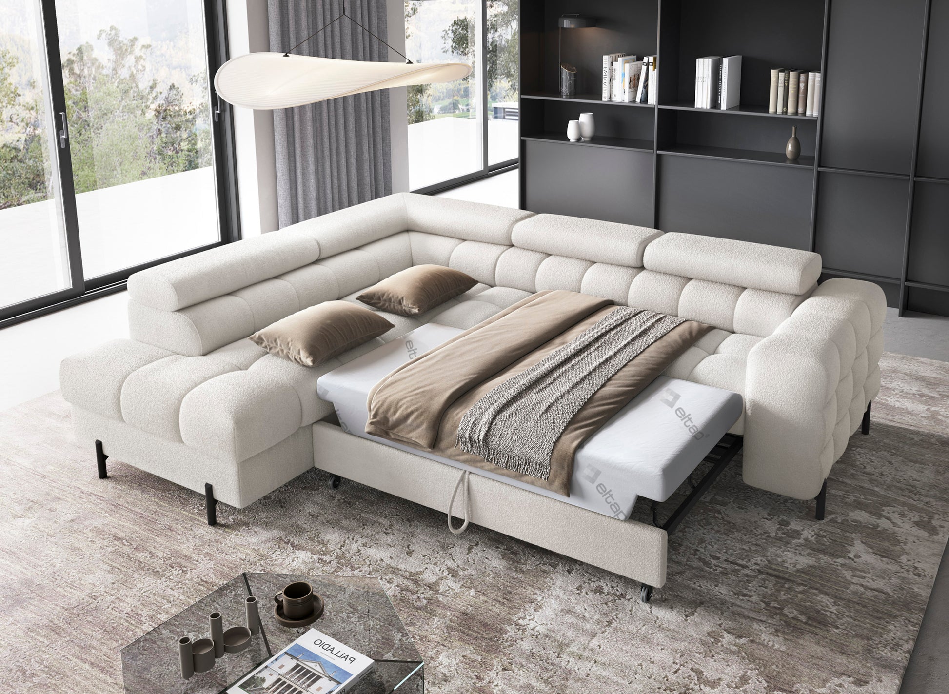 Narożnik Ferucce rozłożony do spania z pościelą i poduszkami, ustawiony w przestronnym salonie z dużymi oknami i nowoczesnym oświetleniem.