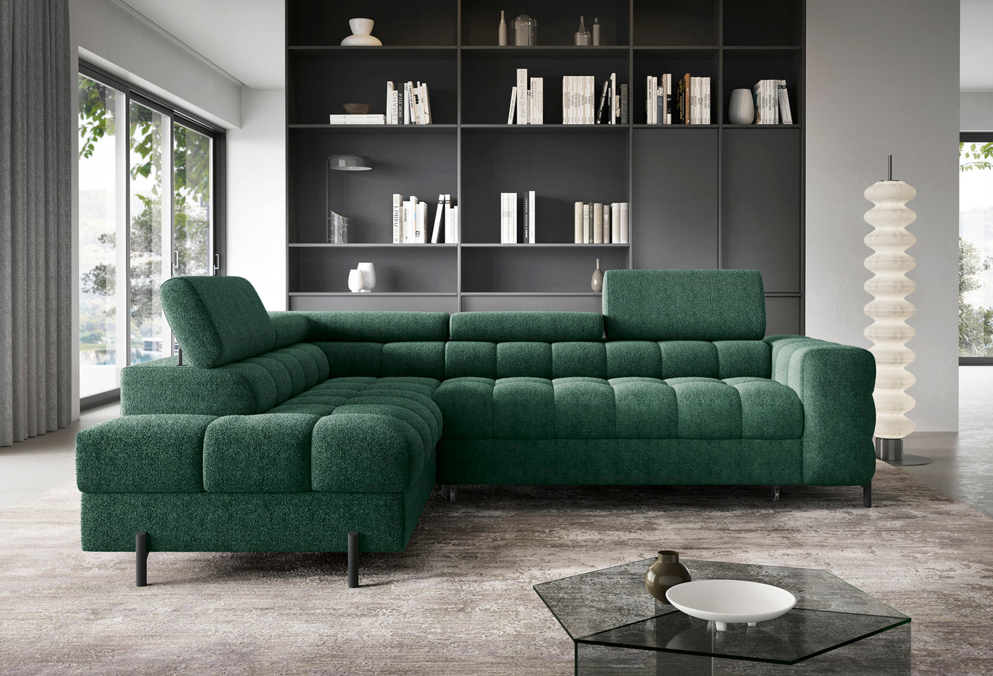 Zielony narożnik Ferucce lewy w tkaninie Amore 35, z pikowanym siedziskiem i regulowanymi zagłówkami, ustawiony we wnętrzu z regałem.